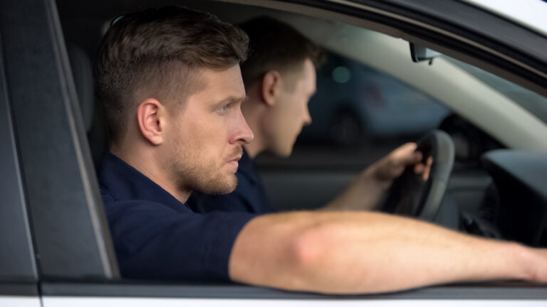 Male security guards sitting in car, monitoring safety, private investigators